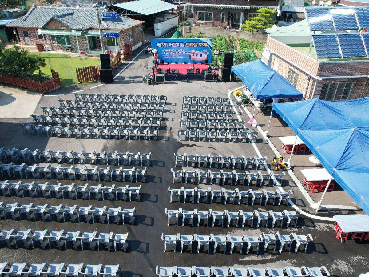 마을가운데 무대좌석이 나란히 배치되어있고 맨 앞에 작은 무대가 시공되어있는 모습을 위에서 바라봄