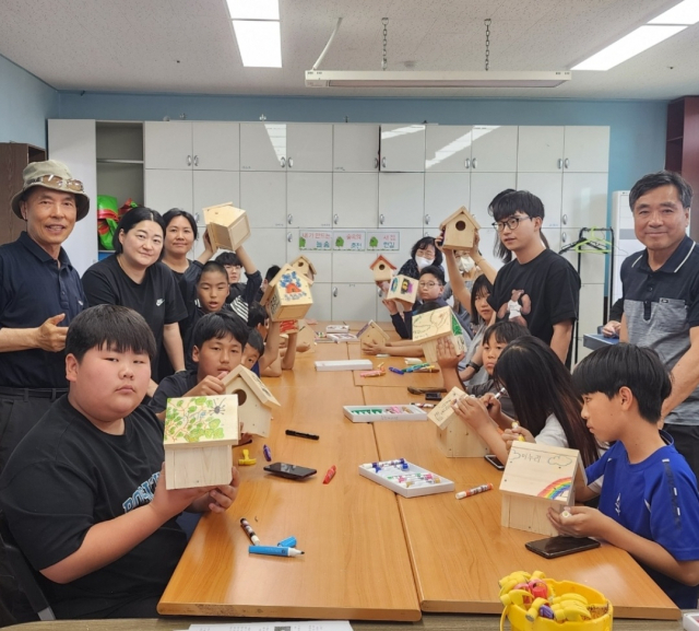 교실에서 약 10여명의 어린이들이 직접 만든 새집을 들고 춘천지역아동센터장, 한길지역아동센터장, 늘솜대표와 함께 사진촬영한 모습